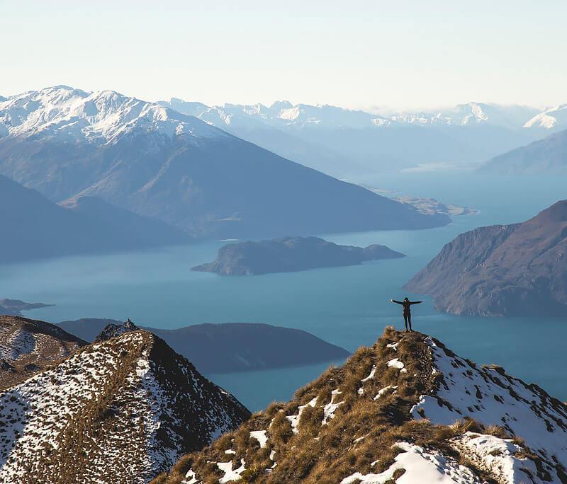 man standing on top of roy's peak